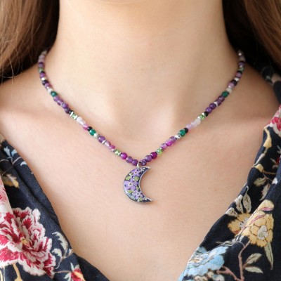 A moon necklace full of stones with a bouquet of flowers